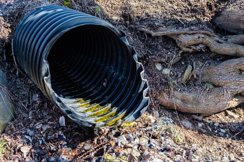 black plastic pipe emerging from ground.