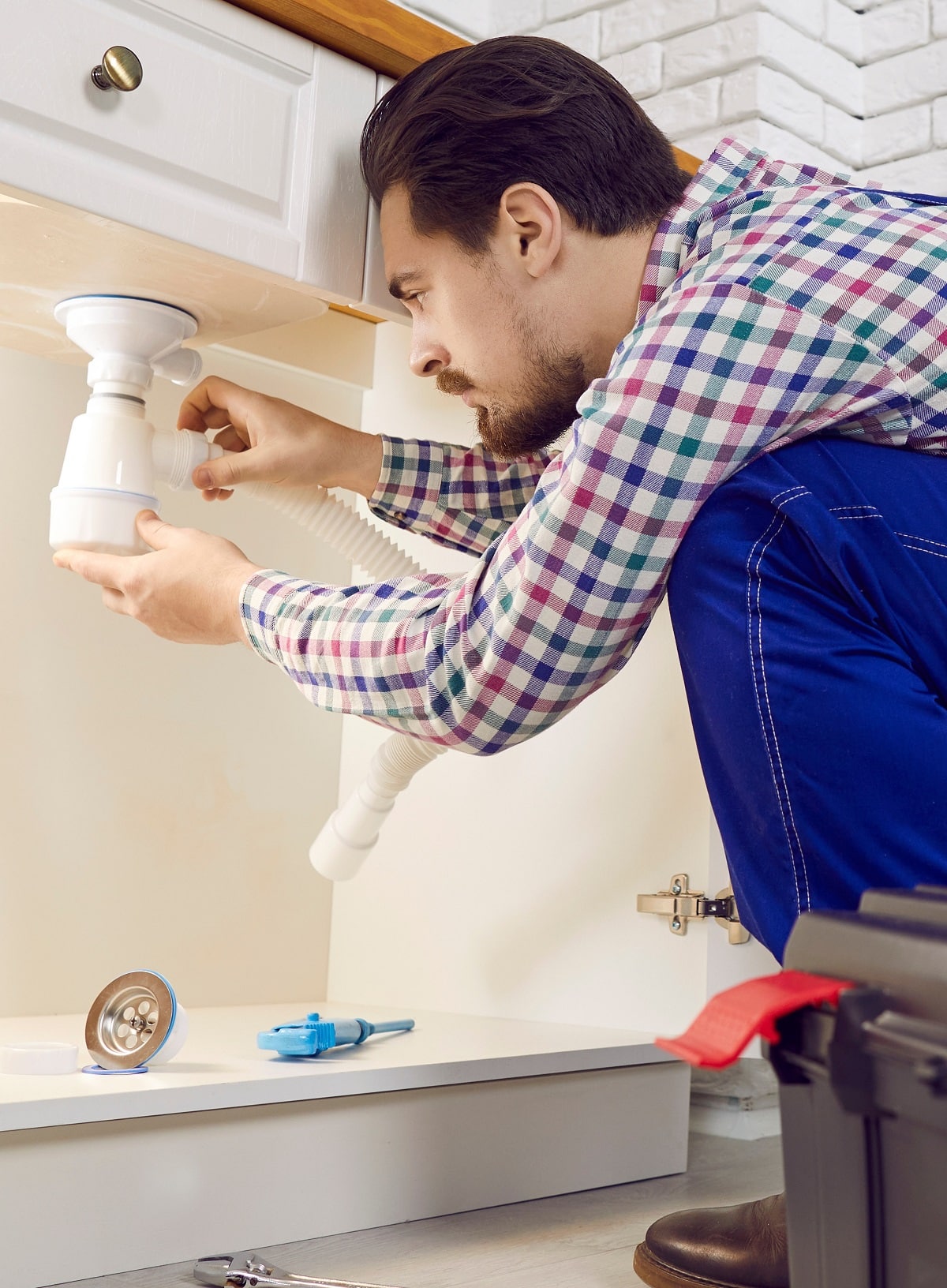 plumber fixing some problems with the kitchen sink, repairing pipes or unclogging the blockage